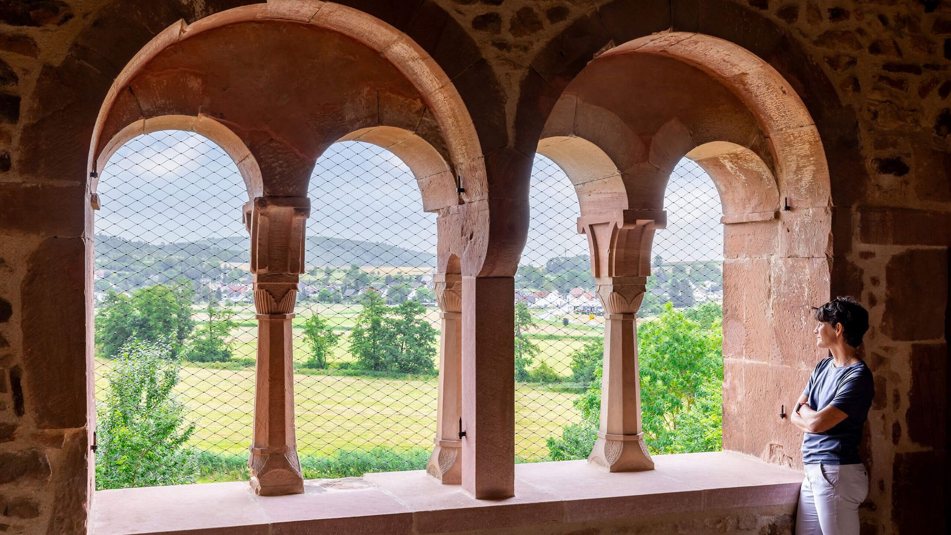 Person blickt durch romanische Arkaden im Kloster Konradsdorf