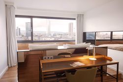 Innenaufnahme eines Zimmers im Scandic Frankfurt Museumsufer mit dem Blick aus dem Fenster auf die Frankfurter Skyline.