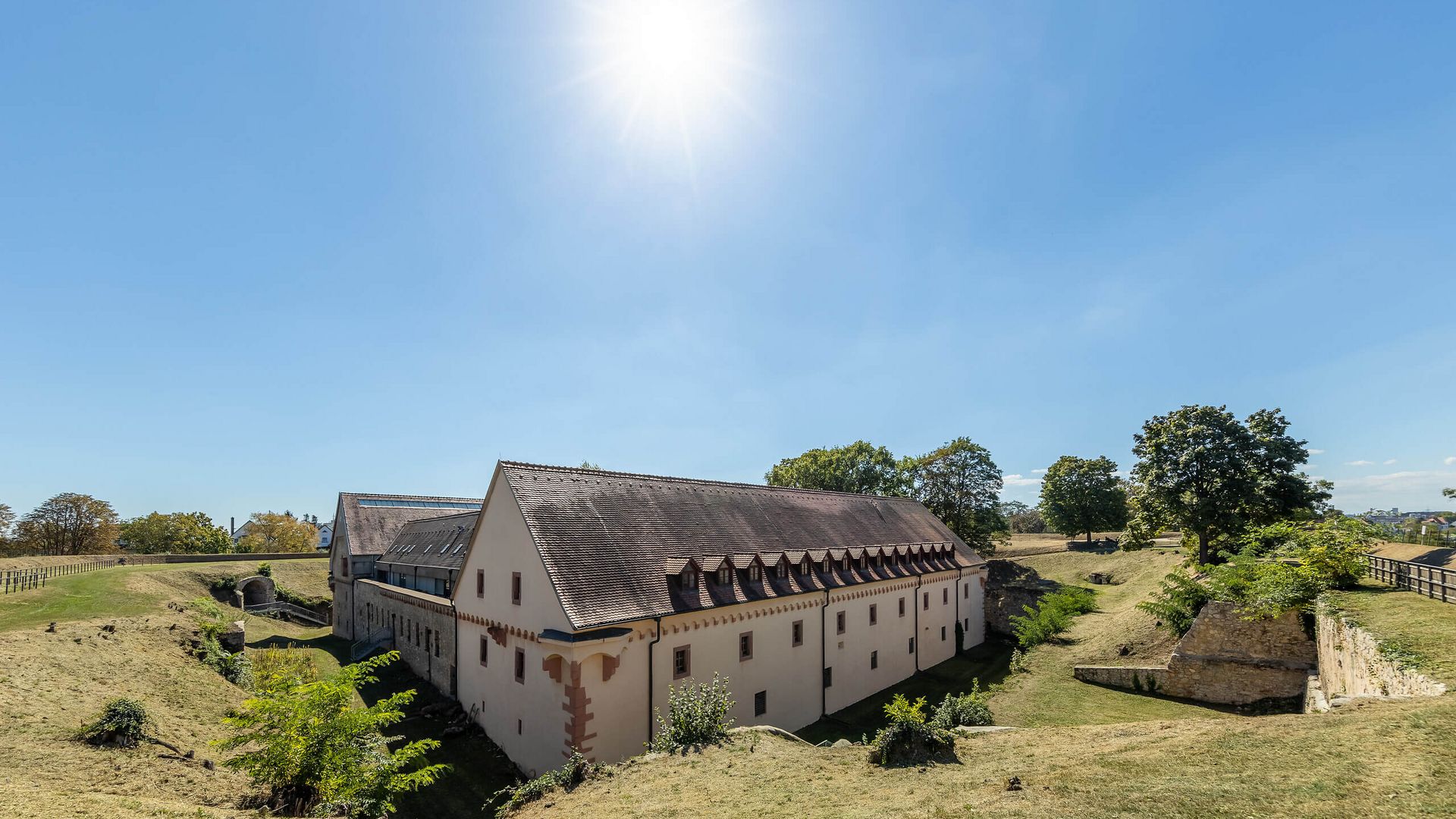 Blick auf die Festung Rüsselsheim mit ihren historischen Mauern und Gräben an einem sonnigen Tag.