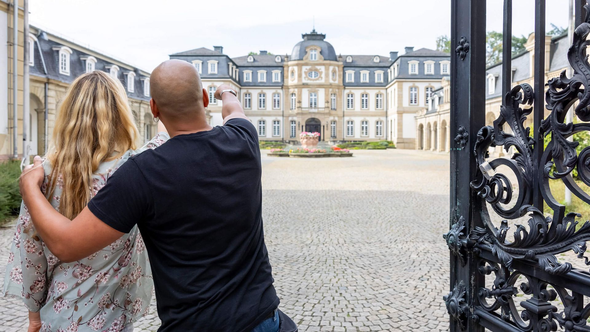 Zwei Personen stehen im Hof eines historischen Palais und blicken auf die barocke Fassade.
