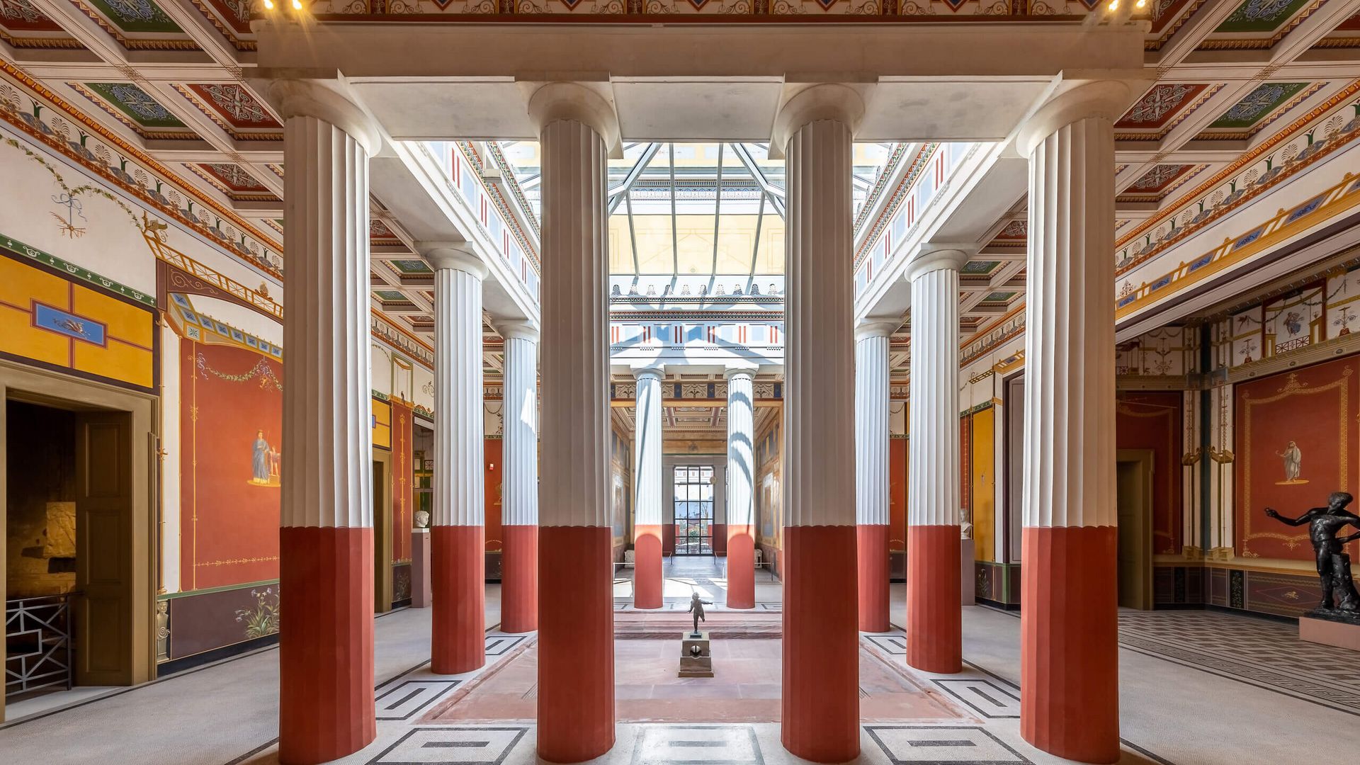 Innenraum des Pompejanums mit Säulen und farbenfroher antiker Wandgestaltung.