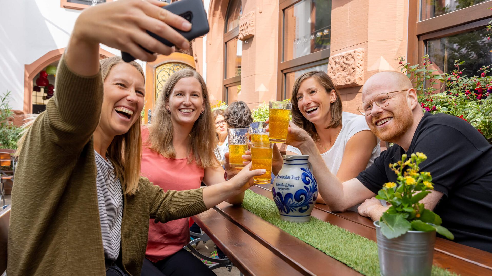 Menschen im typischen Apfelweinrestaurant essen und haben Spaß, prosten sich mit Apfelwein im Gerippten zu.