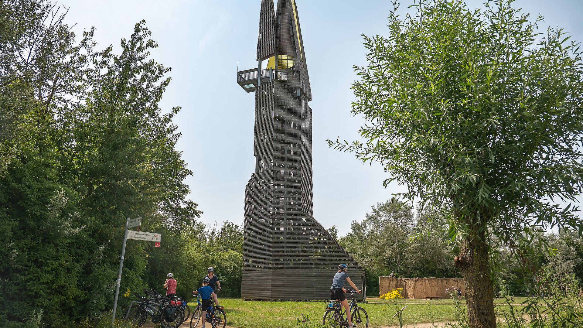 Regionalpark-Aussichtsturm in Flörsheim mit Radfahrenden davor.