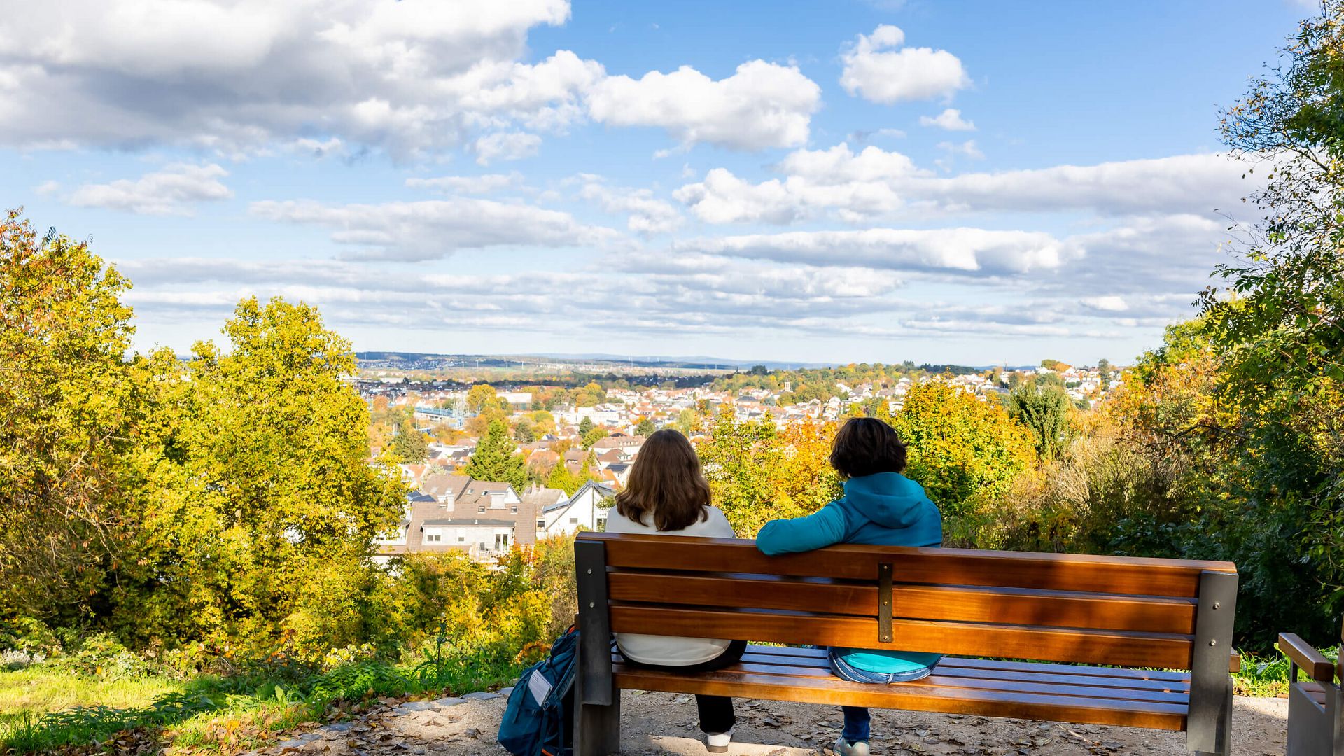 Zwei Personen sitzen auf einer Bank und blicken über Bad Vilbel und das Umland.