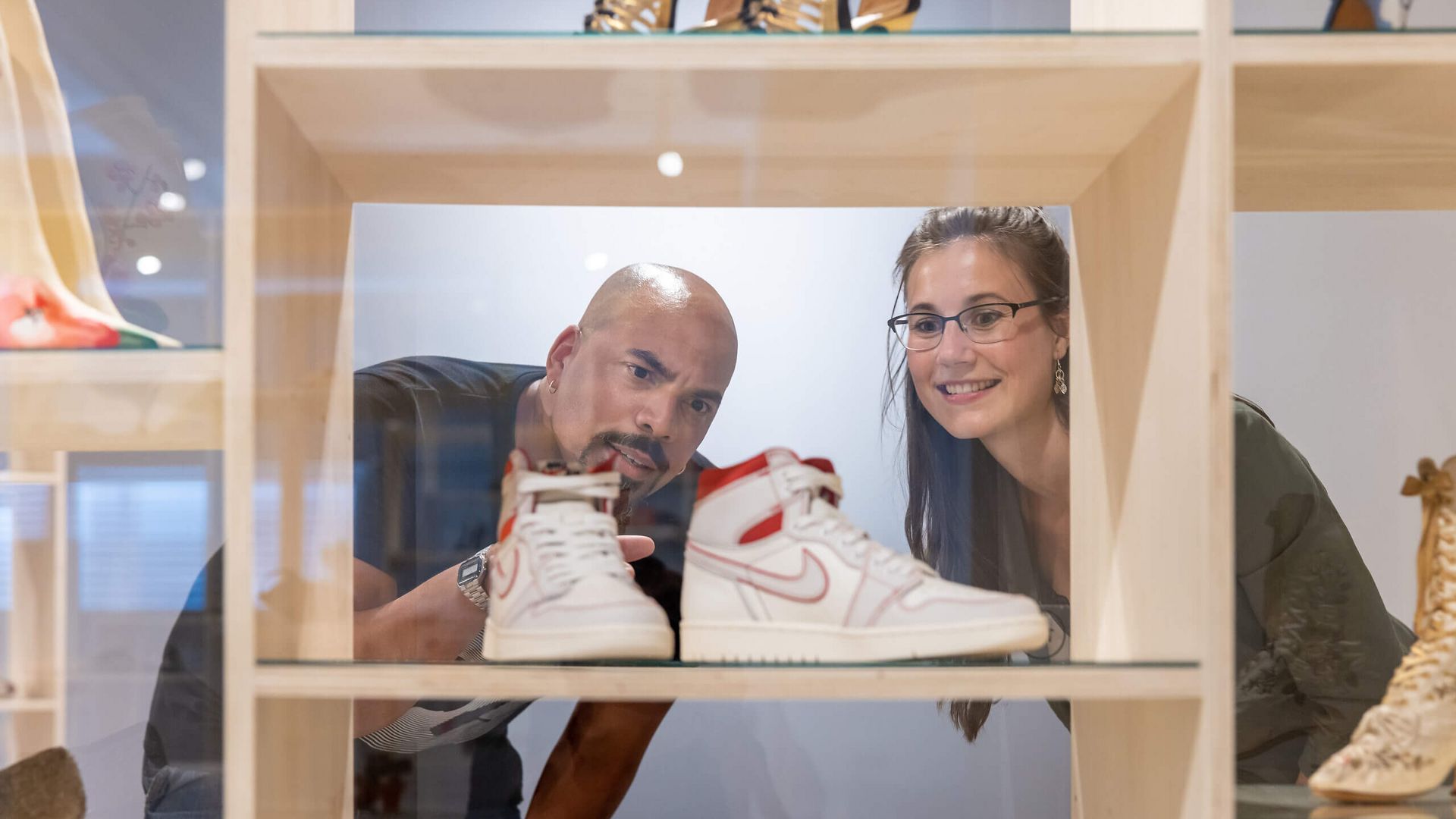 Zwei Personen betrachten Sneaker in einer Vitrine im Ledermuseum.